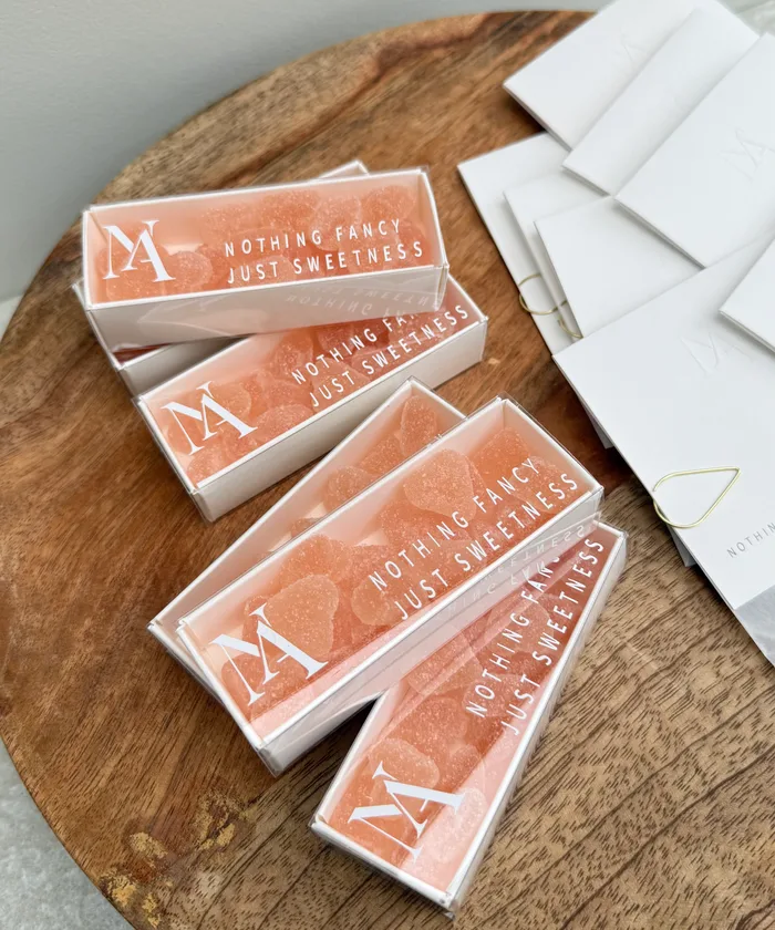 Bedankjes voor het huwelijk van Noémie & Andreas: doosjes met roze snoephartjes, wit N & A-monogram en de tekst "Nothing fancy, just sweetness", door Atelier V
